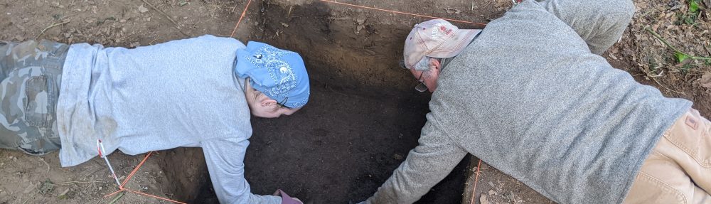 Two students laying down and excavating in a unit